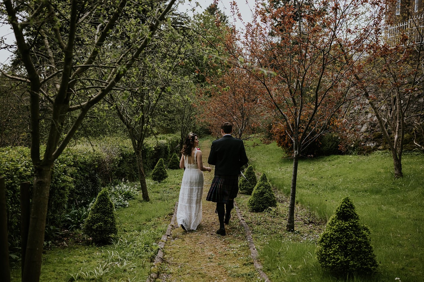 Parc du château de Drumtochty mariée marié dentelle portrait Catherine Deane robe de mariée kilt tartan traditionnel à pied bordée d'arbres