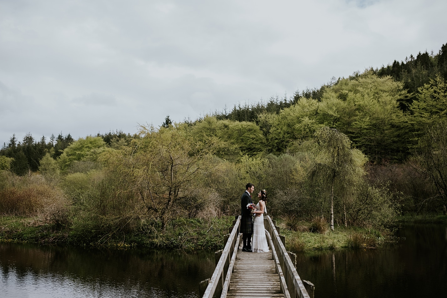 Parc du château de Drumtochty loch passerelle en bois mariée marié portrait dentelle Catherine Deane robe de mariée kilt tartan traditionnel