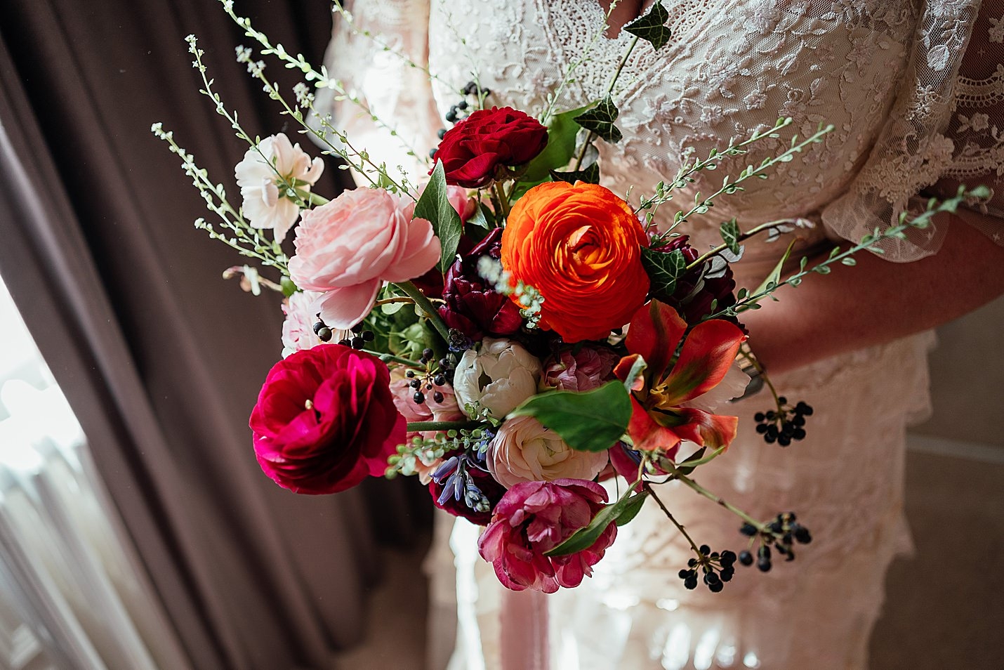 mariée en robe de dentelle blanche tenant un bouquet de mariée avec des verts rouges roses oranges tambour château mariage fotomaki photographie