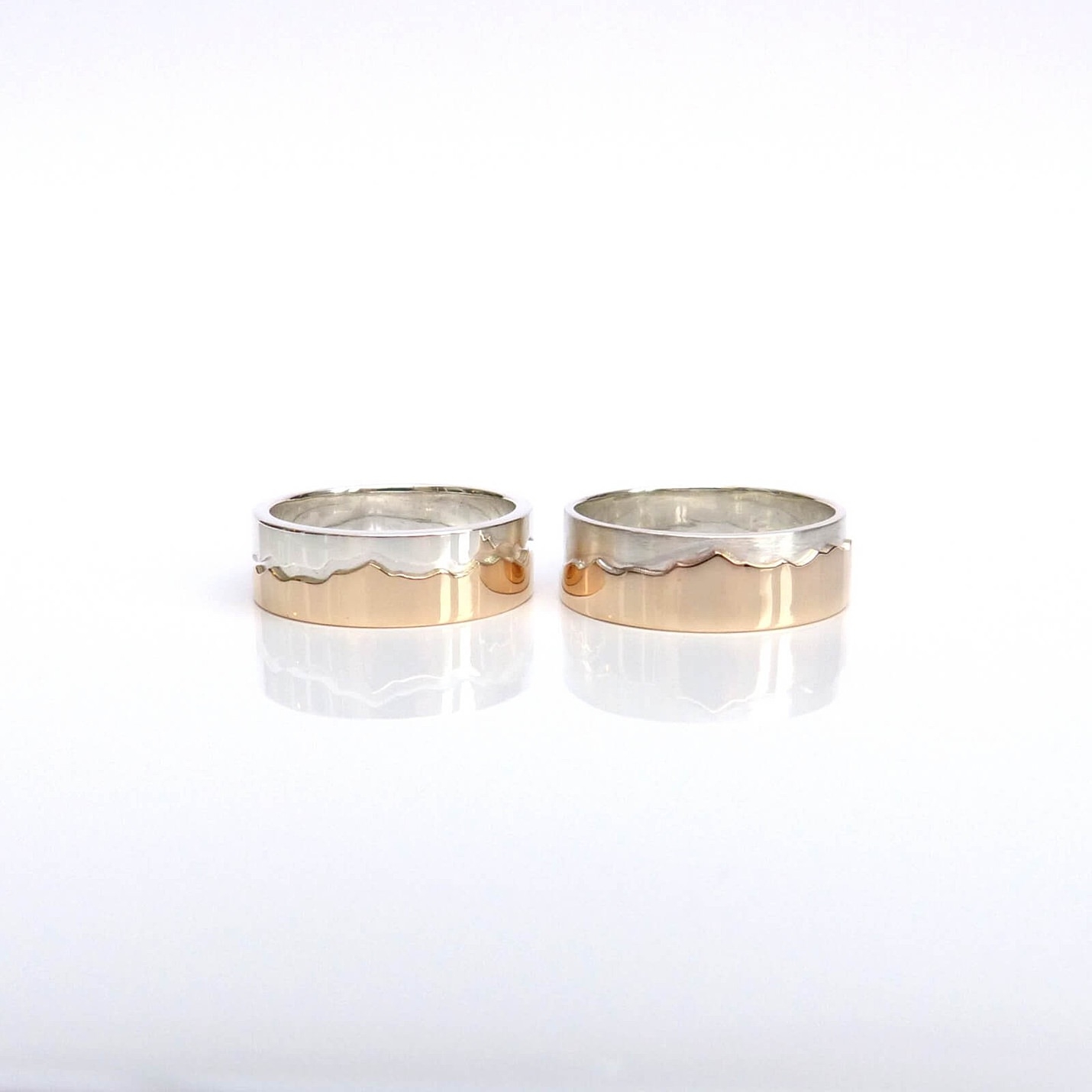 two bespoke wedding rings which are rose gold and silver with outline of mountain range around the rings jen cunningham bespoke wedding jewellery scotland