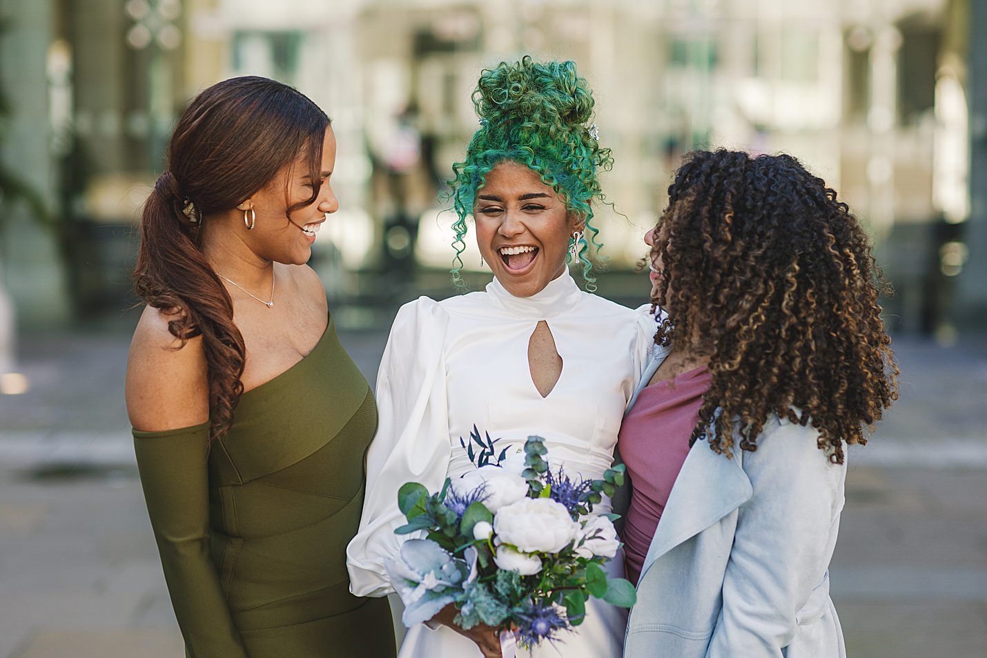bride laughing with friend at either side of her smiling outside venue marischal college wedding clarke joss photography
