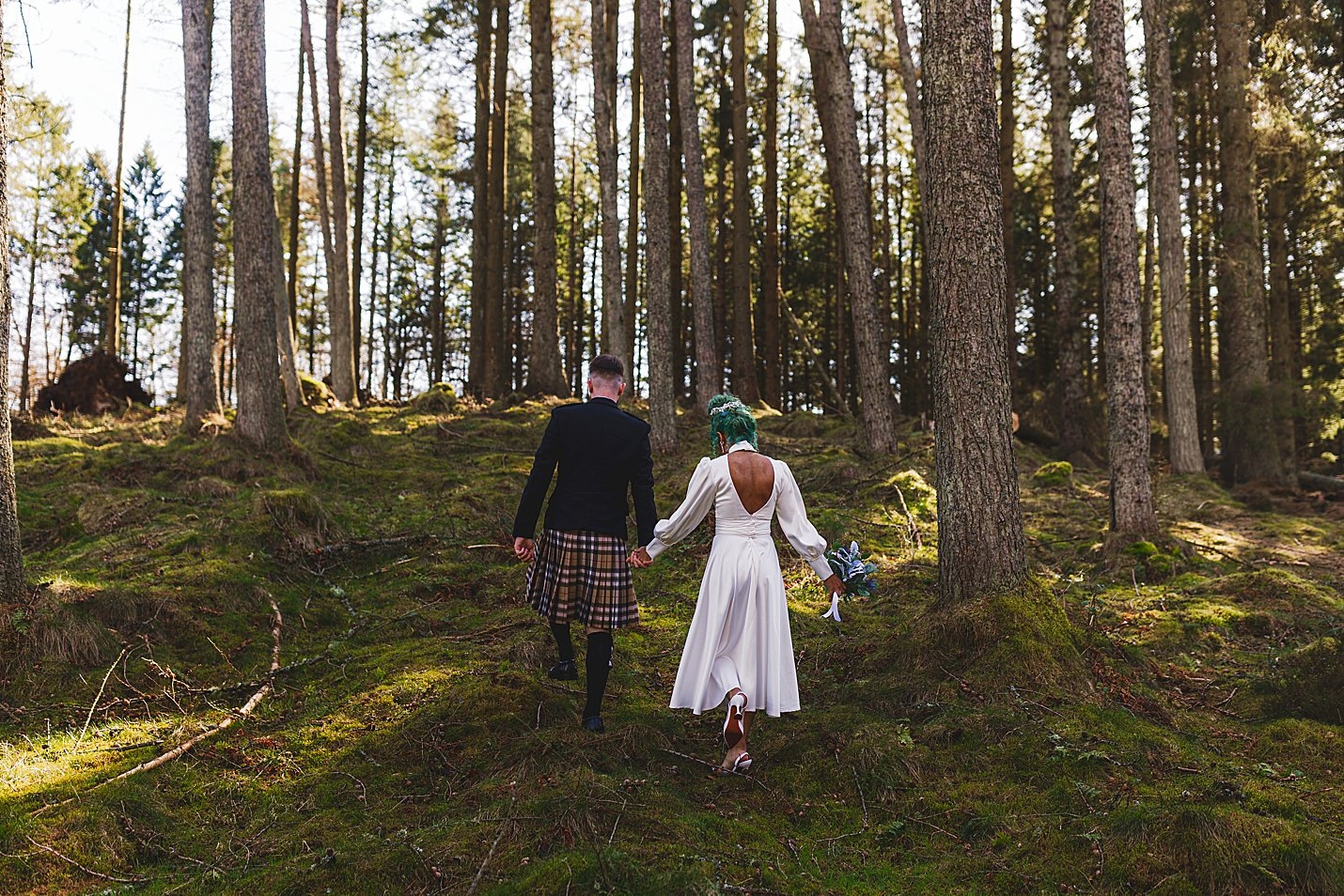 bride and groom walking up hill in forest away from camera marischal college wedding clarke joss photography
