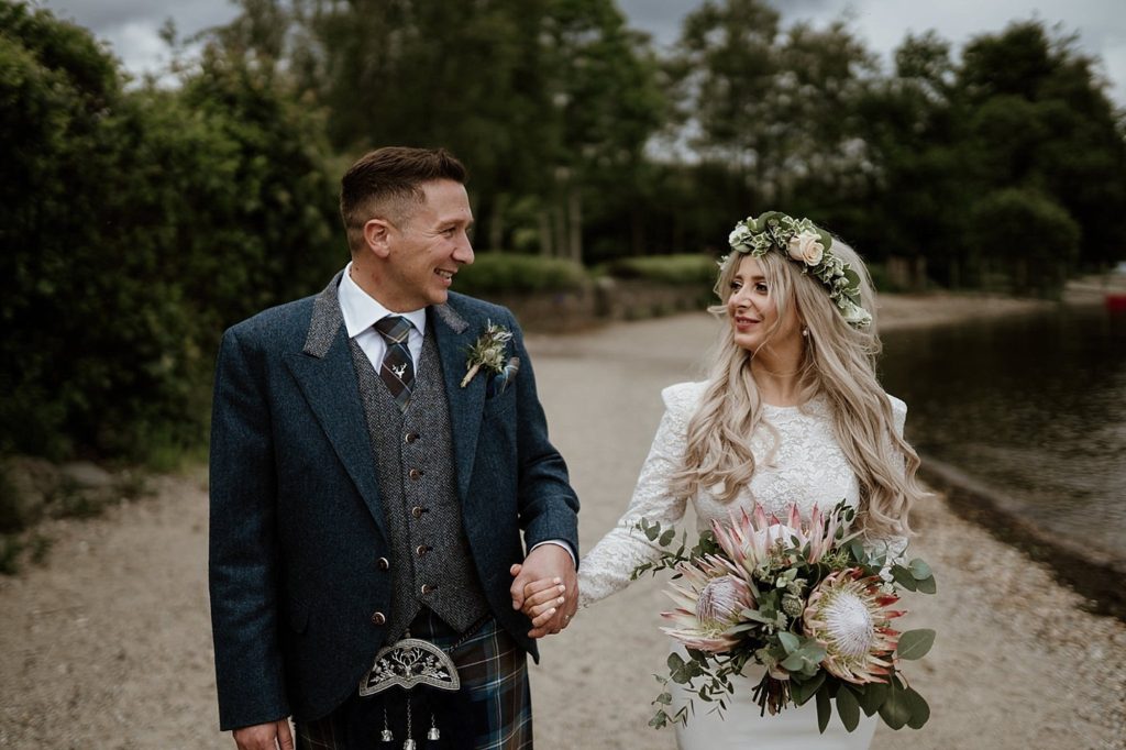 Boho-inspired bride wears a flower crown and carries a protea bouquet and groom wears a modern kilt outfit