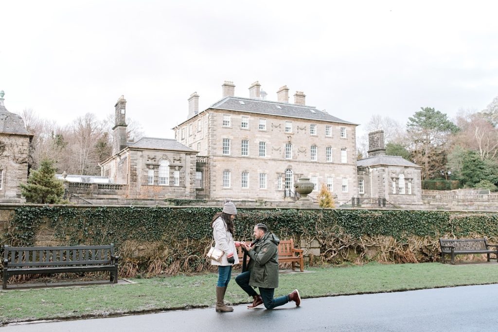 Man is down on one knee proposing to his girlfriend in front of Pollok House stately home