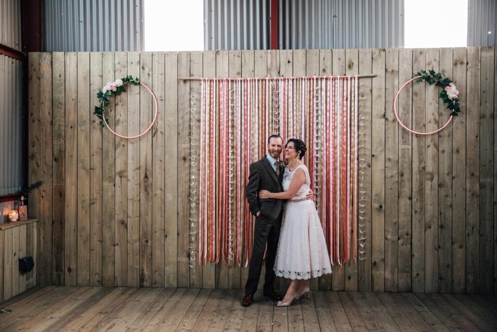 dalduff barn wedding ayrshire interior red barn flower hoops ribbon backdrop decorated bride short wedding dress