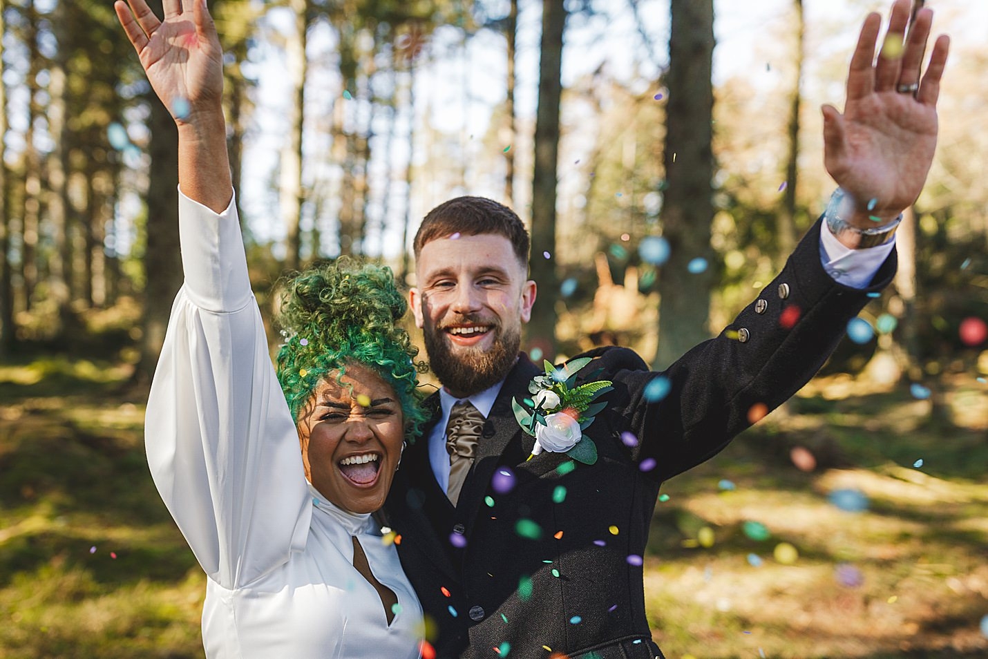 bride and groom pose with their hands in the air as they throw confetti in the forest marischal college wedding clarke joss photography